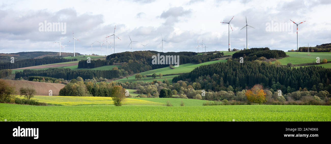 Le turbine eoliche e semi di senape campo nel paesaggio rurale del sud Eifel in Germania sotto il nuvoloso cielo di autunno Foto Stock