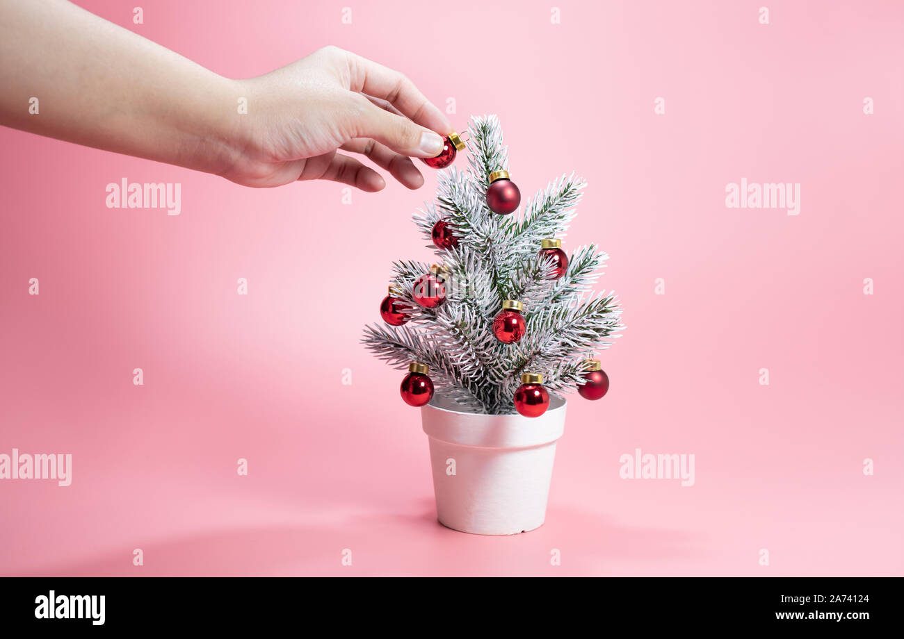 Festa di Natale concetti idee femmina con decorazione a mano carino pino con sfera ornamento sui colori pastello sfondo. celebrazione del design della scheda. Foto Stock