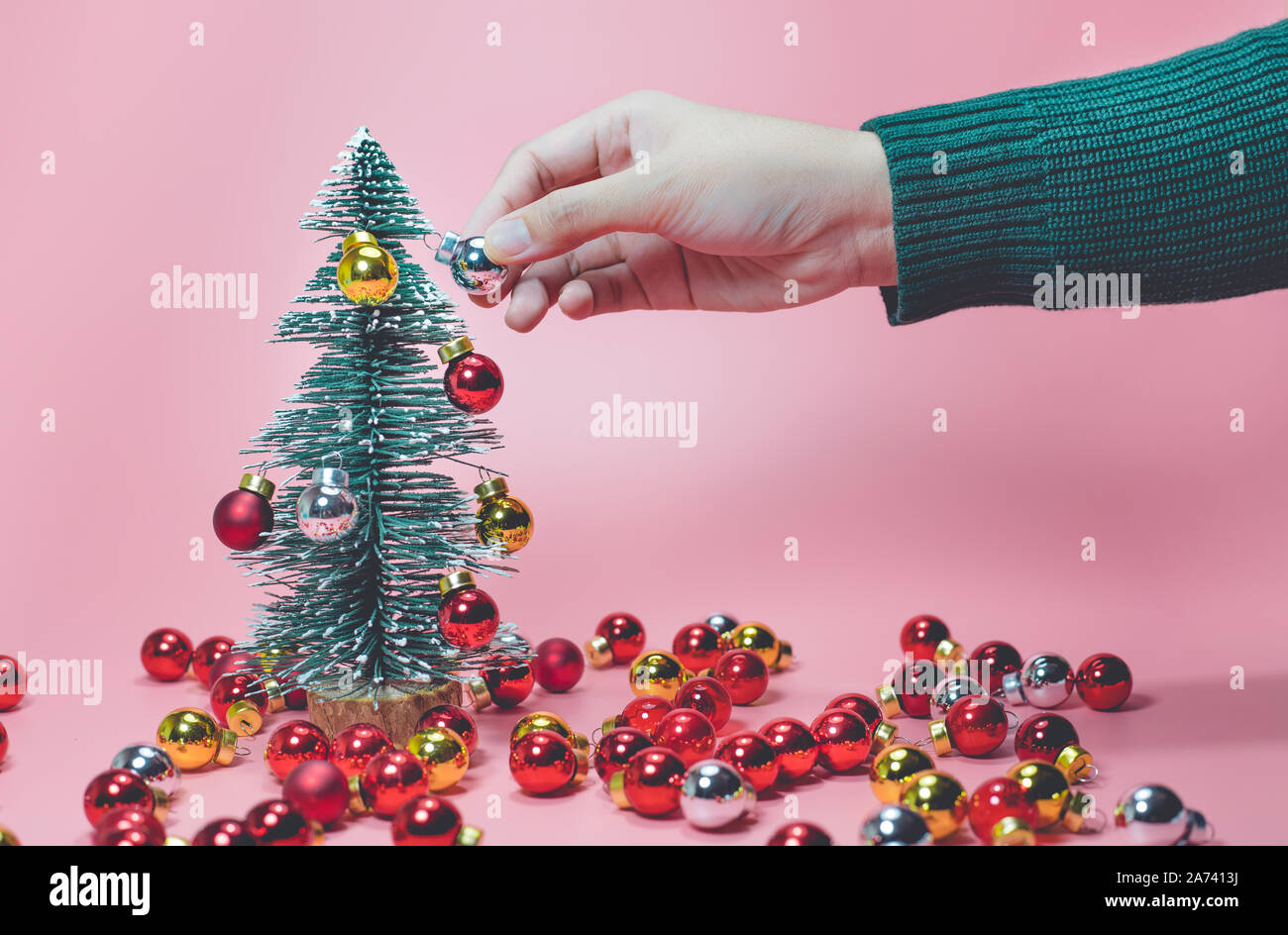 Festa di Natale concetti idee femmina con decorazione a mano carino pino con sfera ornamento sui colori pastello sfondo. celebrazione del design della scheda. Foto Stock