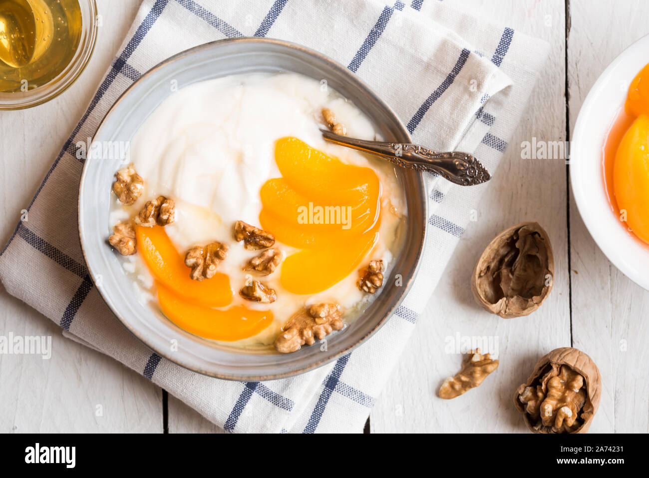 Yogurt con pesche, noci e miele in una ciotola blu Foto Stock