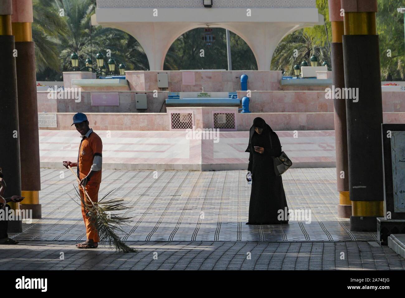 Muscat Oman una spazzatrice e una donna al Al Qurum giardini, un perfettamente curati e abbeverati oasi in un deserto polveroso città. | Utilizzo di tutto il mondo Foto Stock