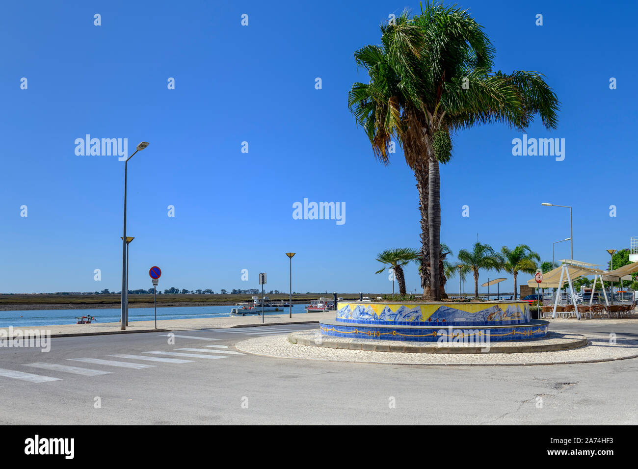 Palme sul lungomare e passeggiata a Santa Luzia contro la Ria Formosa. Santa Luzia Algarve, Portogallo. Foto Stock