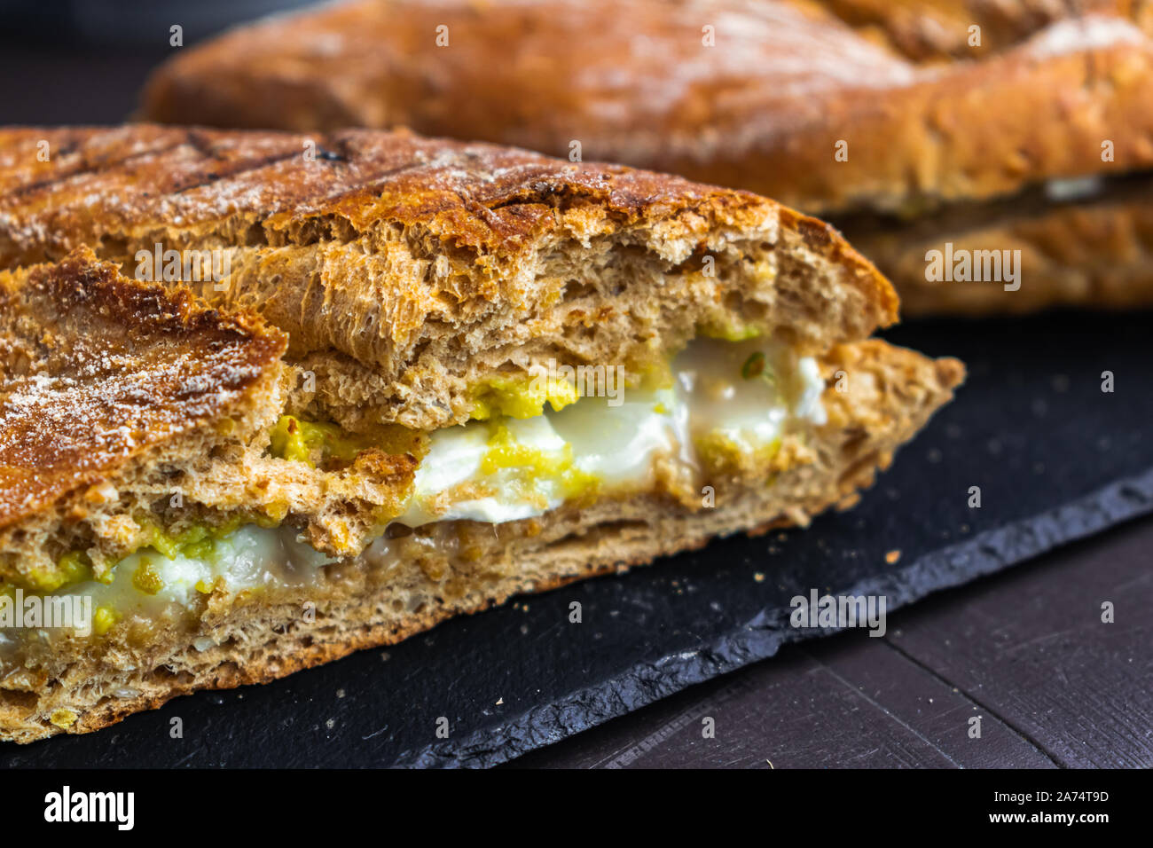 Pane rustico con avocado formaggio e miele, sulla superficie nera Foto Stock