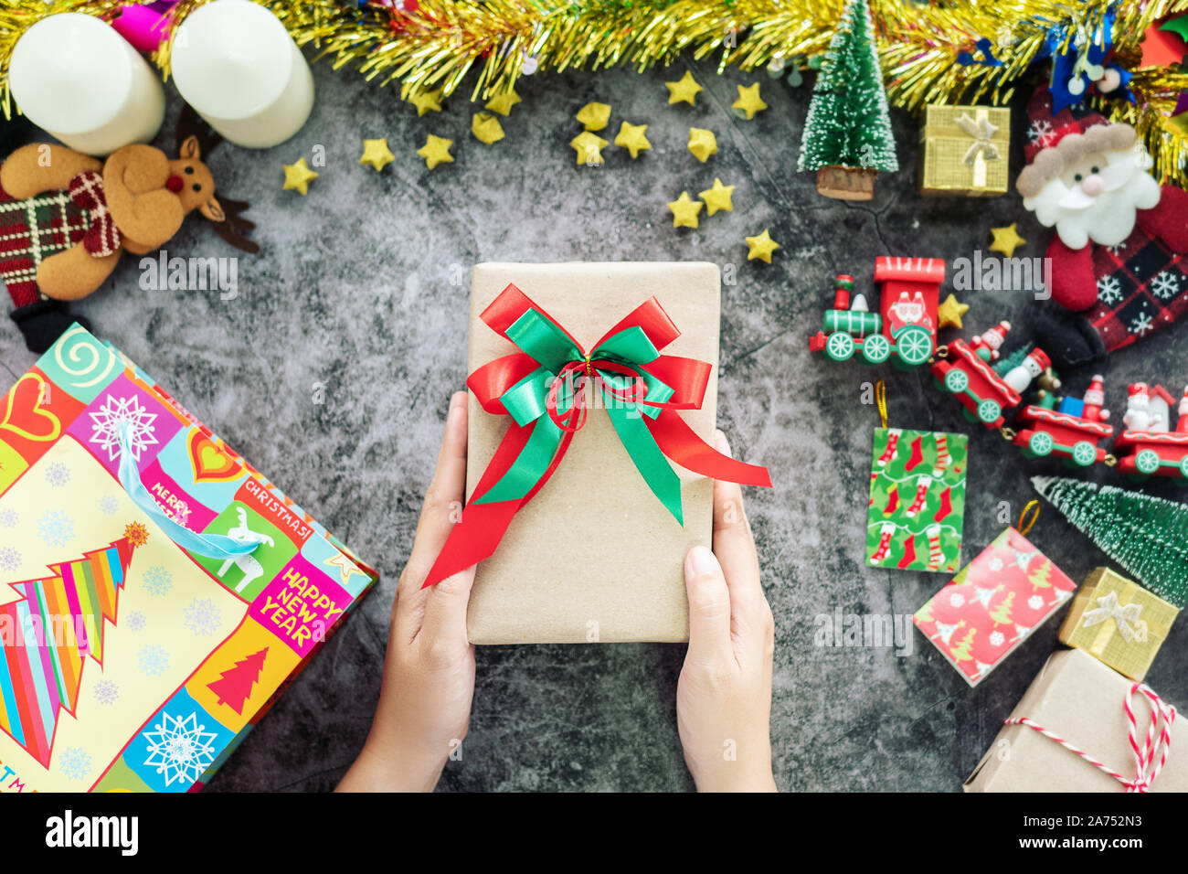 Mano azienda confezione regalo da shopping bag durante la stagione di natale e festival di regali, decorazioni con ornamento di Natale sul tavolo Foto Stock