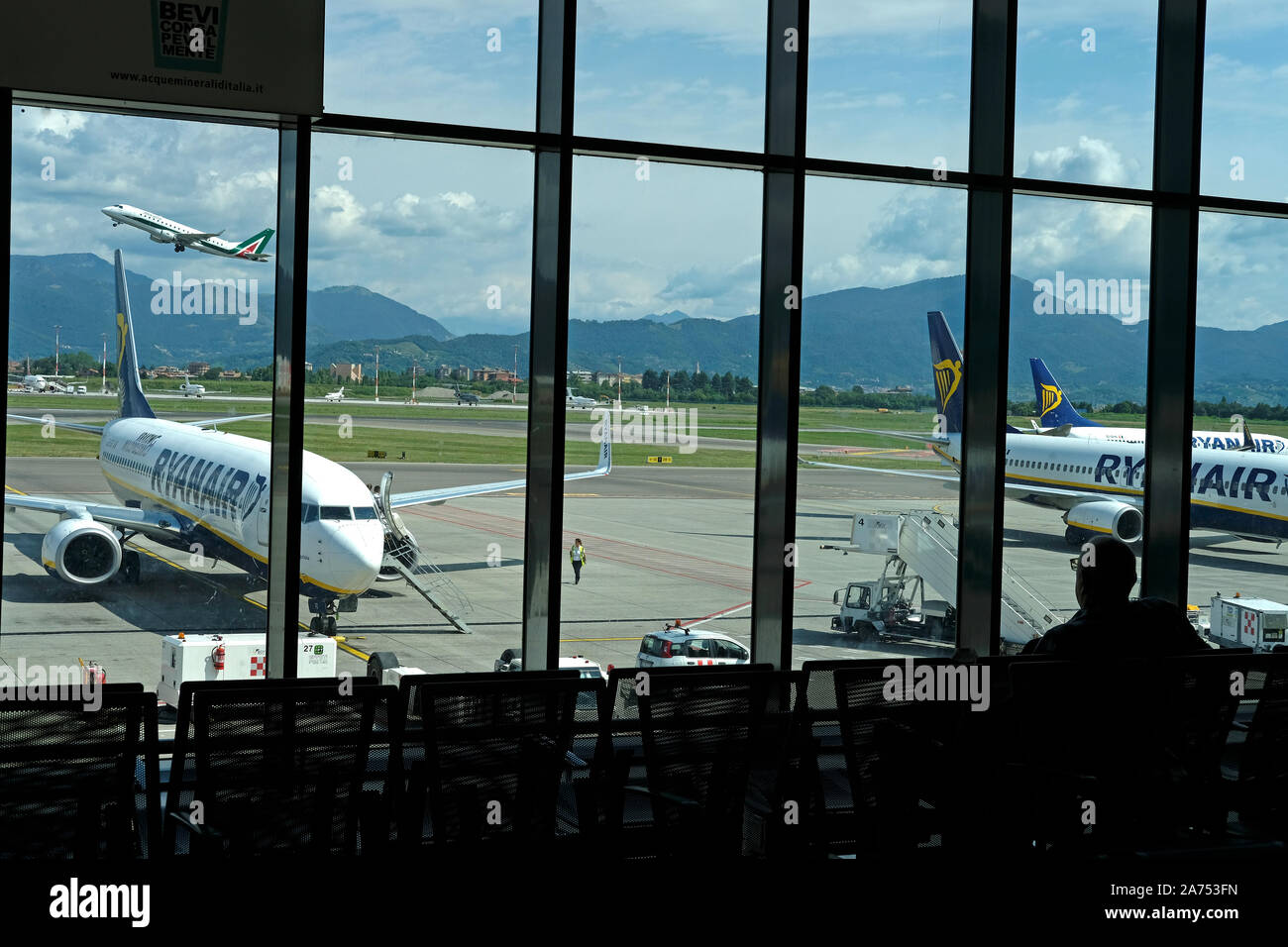 I passeggeri di salire a bordo di un aereo Ryanair mentre un altro aereo decolla Foto Stock
