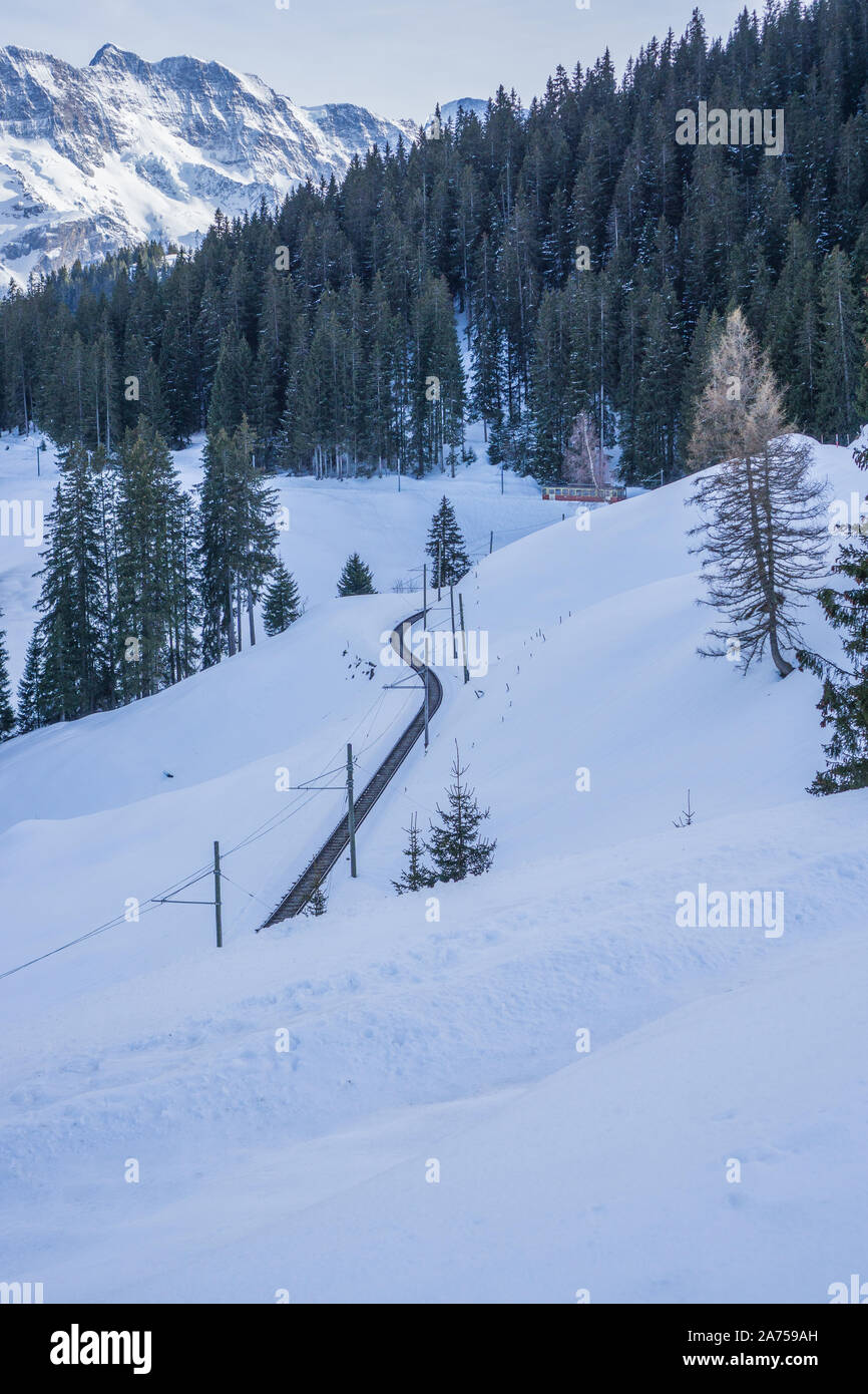 Camminando tra Murren villaggio in Svizzera alla stazione della funivia in un bellissimo percorso attraverso un sorprendente montagne innevate paesaggio. Foto Stock