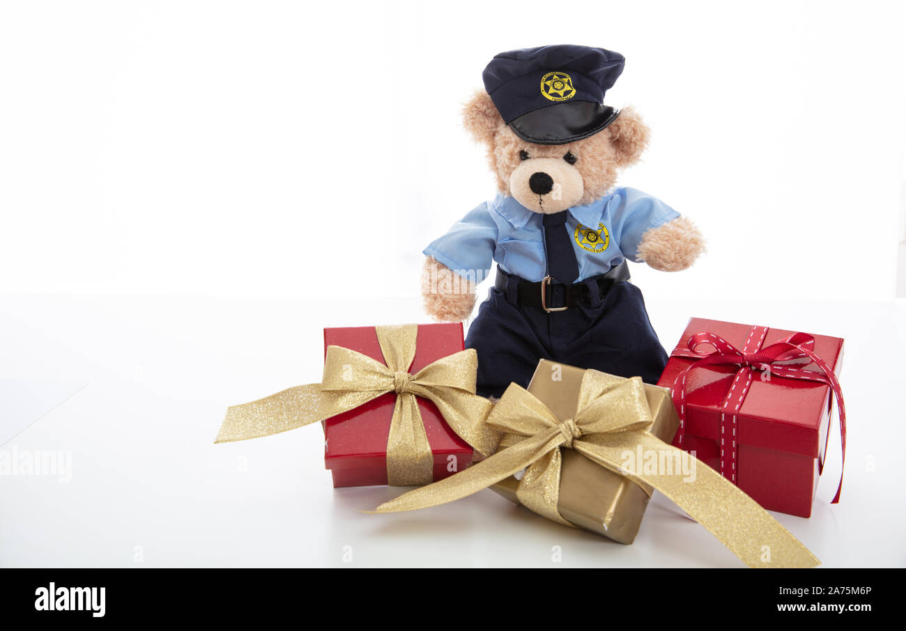 Polizia e concetto di natale. Simpatico orsacchiotto in funzionario di polizia uniforme e xmas confezioni regalo isolata contro uno sfondo bianco Foto Stock