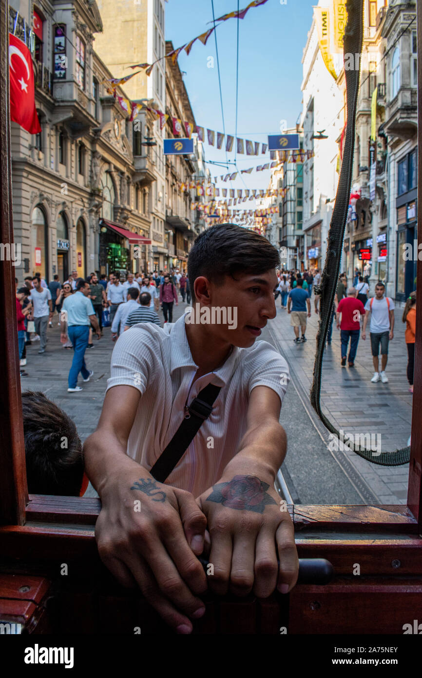 Istanbul: un ragazzo turco appeso sulla storica T2 Linea tram Taksim-Tunel proveniente dalla piazza Taksim sulle rotaie del famoso viale Istiklal Caddesi Foto Stock