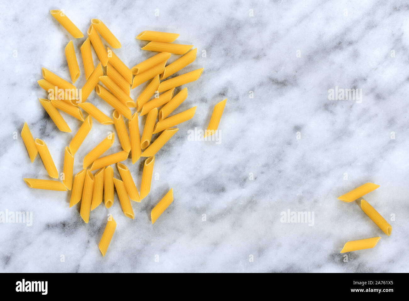 Originale Italiano Penne Rigate Pasta su marmo bianco dello sfondo. Puristic cucina italiana tema con copia spazio per il testo e la progettazione ad alta risoluzione. Foto Stock