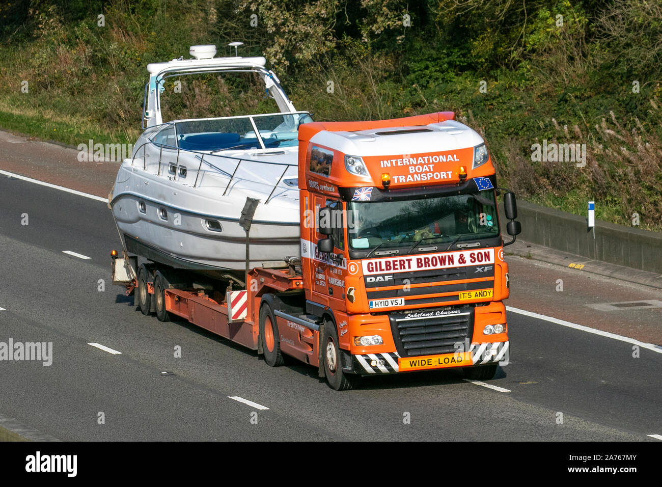 Andy guida Gilbert Brown & Son UK traffico veicolare, trasporto internazionale di barche, veicoli DAF, indivisibile carico anormale in direzione sud sull'autostrada M6 a 3 corsie. Foto Stock