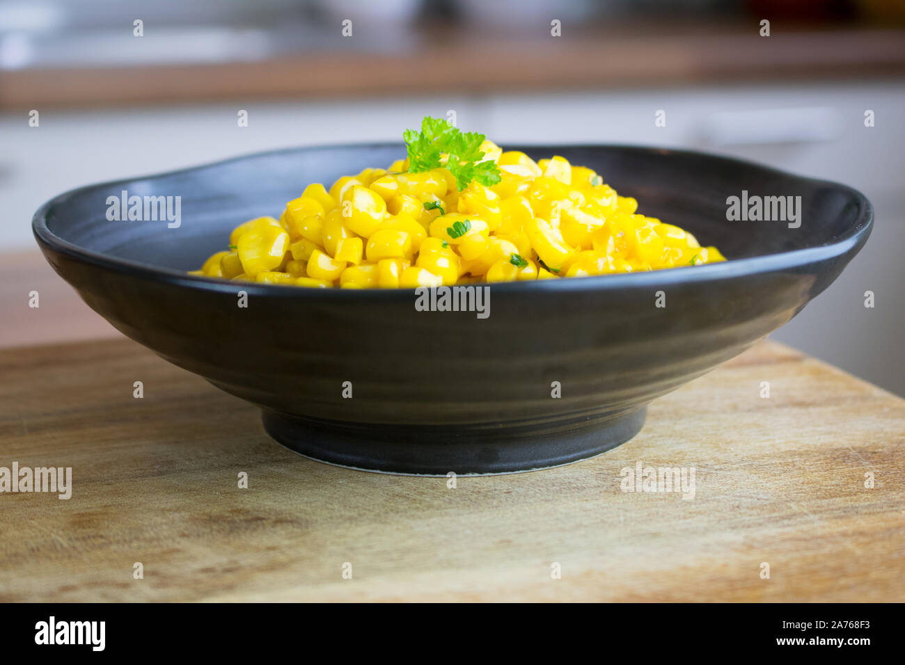 Fotografia di cibo di un nero vaso di ceramica con un piatto di lato di mais su un bancone cucina top Foto Stock