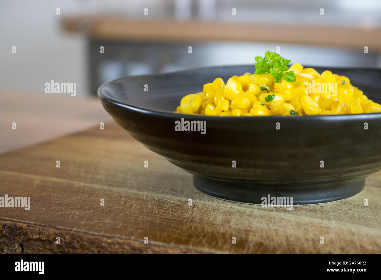Fotografia di cibo di un nero vaso di ceramica con un piatto di lato di mais su un bancone cucina top Foto Stock