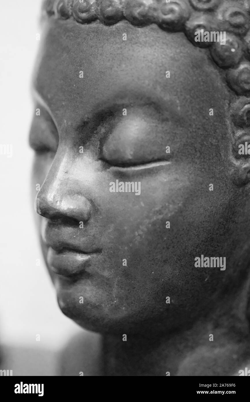 Immagine monocromatica di una faccia di una statua di Buddha su uno sfondo bianco closeup Foto Stock