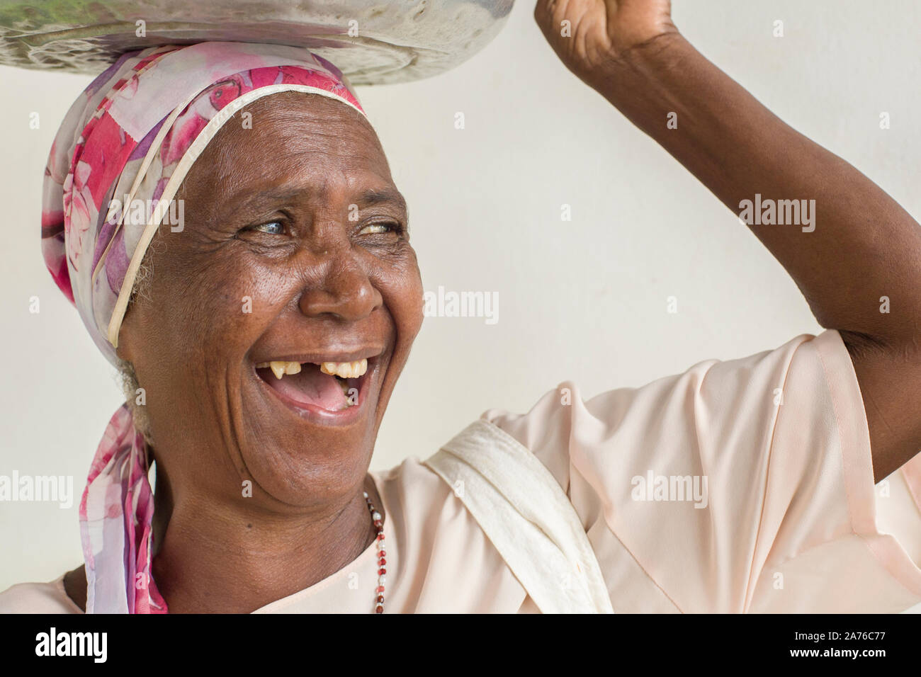 Almenara, Minas Gerais, Brasile - 22 Gennaio 2016: Tradizionale lavandaia ridere mentre si tiene un bacino pieno di vestiti sulla testa Foto Stock