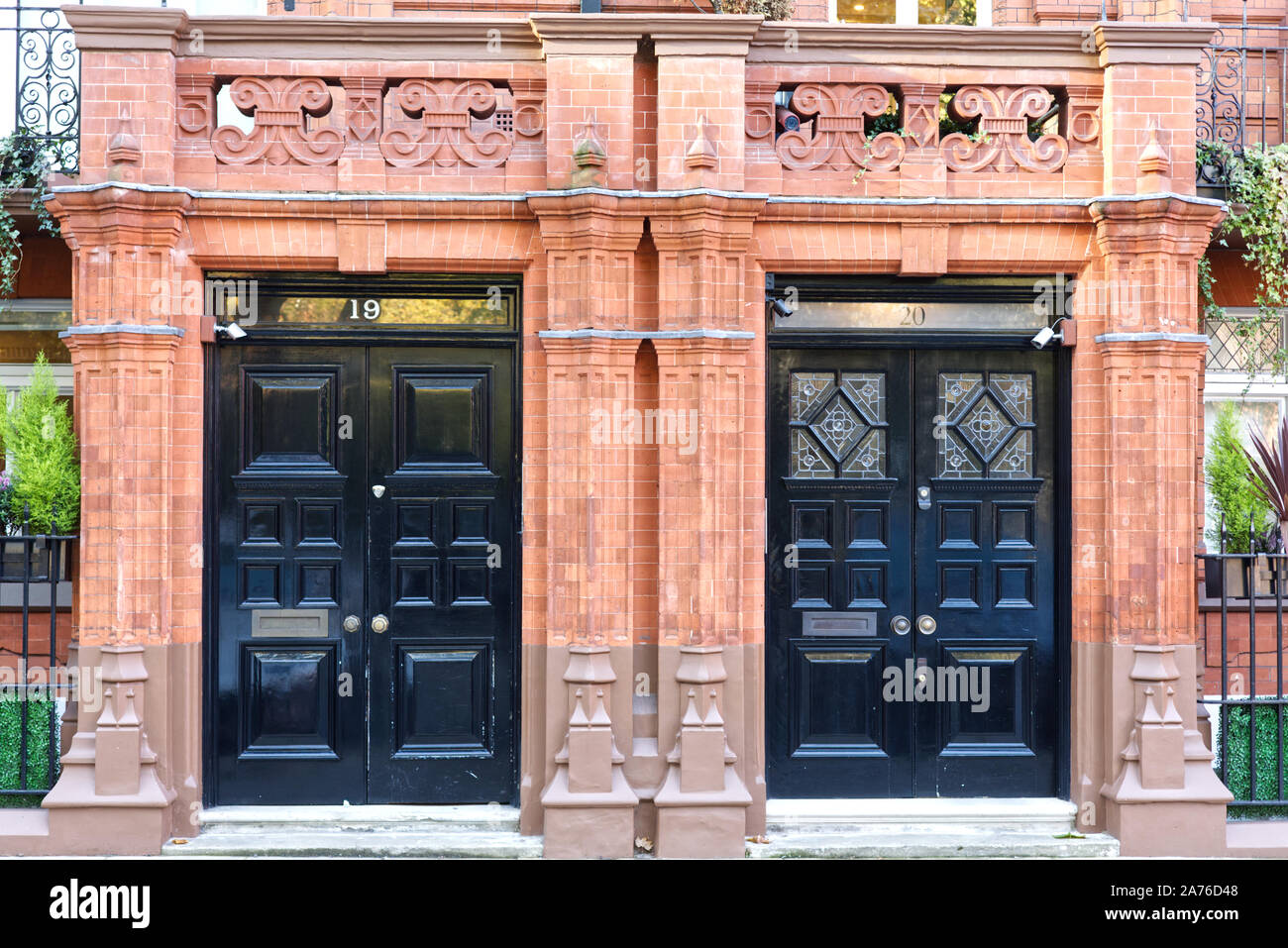 Lavoro in pietra sulla facciata dei palazzi e porte in legno Chelsea Londra Foto Stock