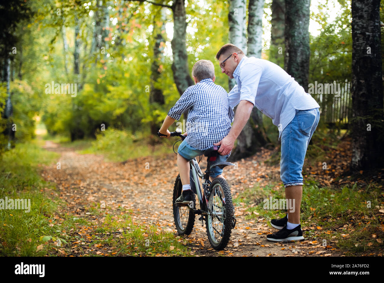 Giovane padre insegnando il suo figlio ad andare in bicicletta Foto Stock