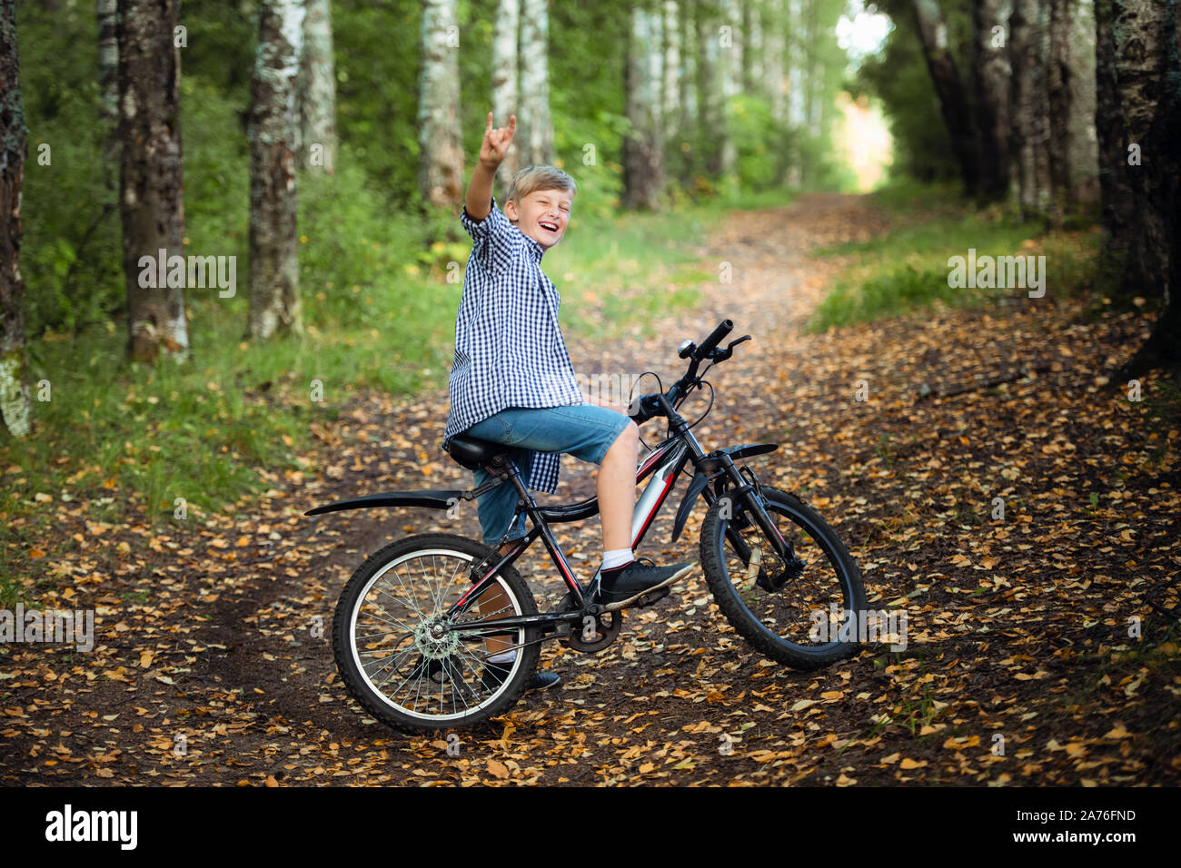 Felice ragazzo su una bicicletta nel parco degli studi a ride frenato bruscamente su una sporcizia. Foto Stock