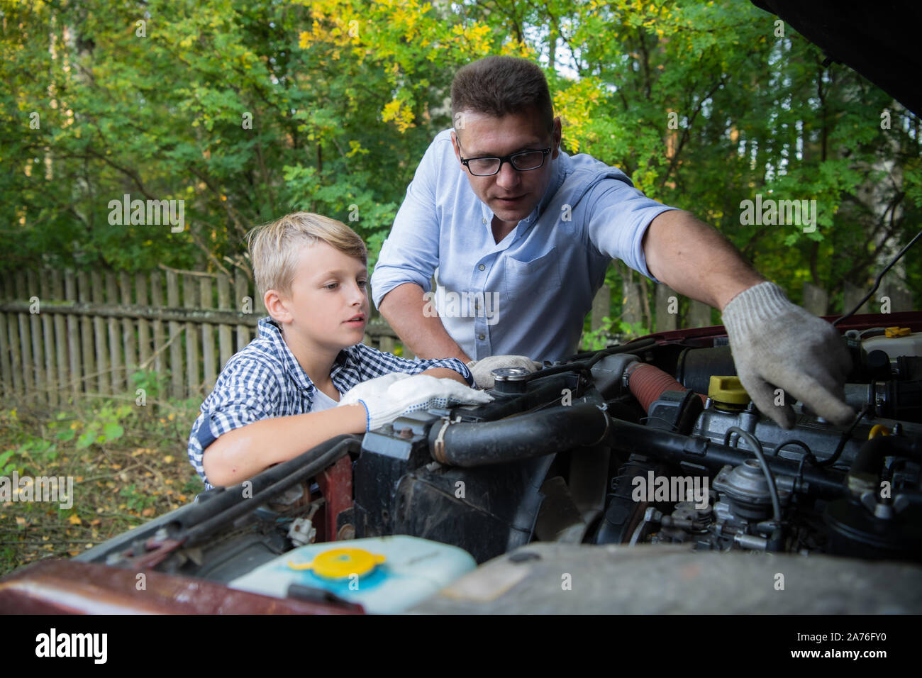 Insegnamento di padre di suo figlio come controllare il livello dell'olio sulla macchina di famiglia. Foto Stock