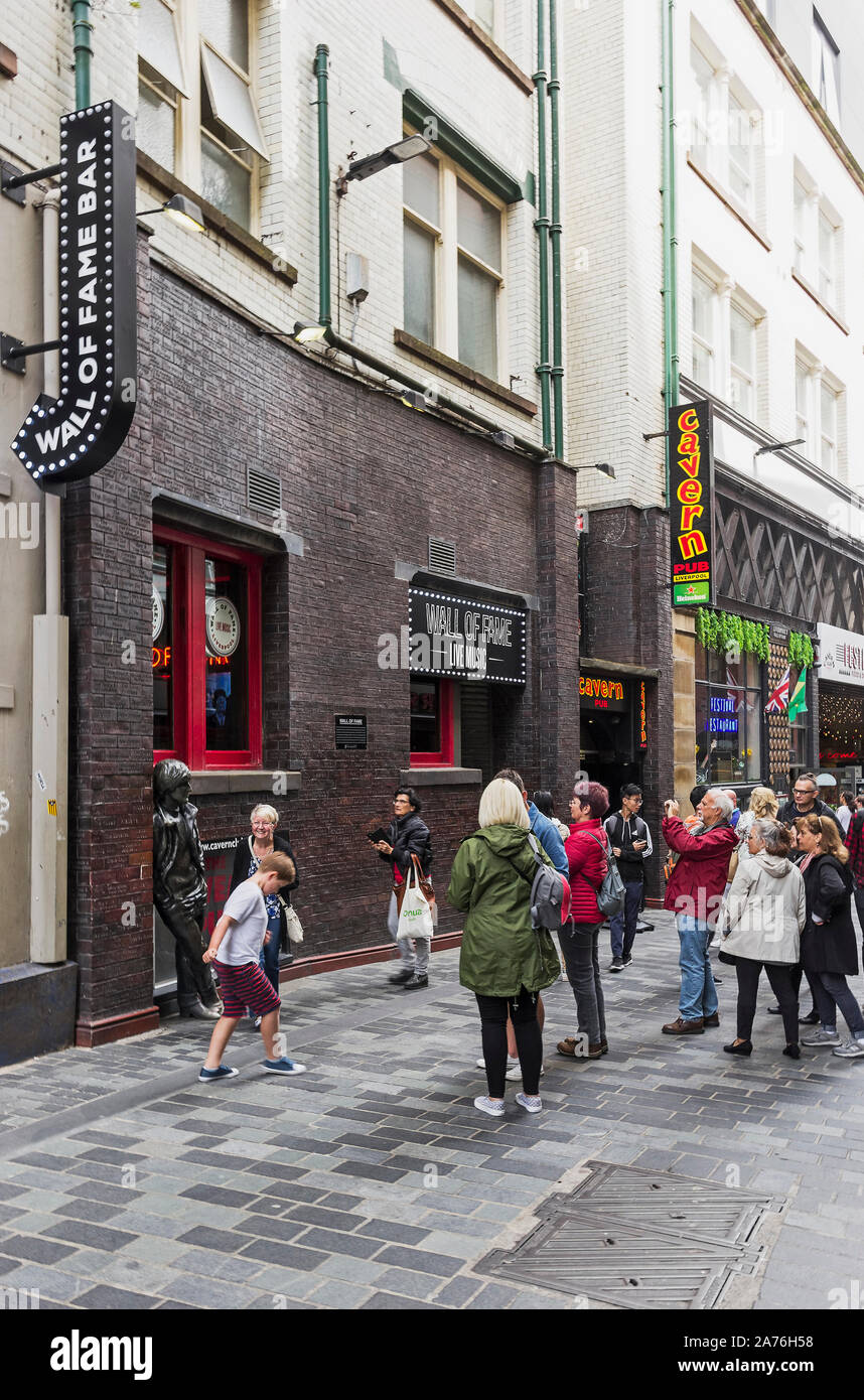 I turisti scattare foto con un John Lennon statua al di fuori del Muro delle Celebrità Bar e Pub in caverna su Mathew Street, Liverpool, Regno Unito Foto Stock