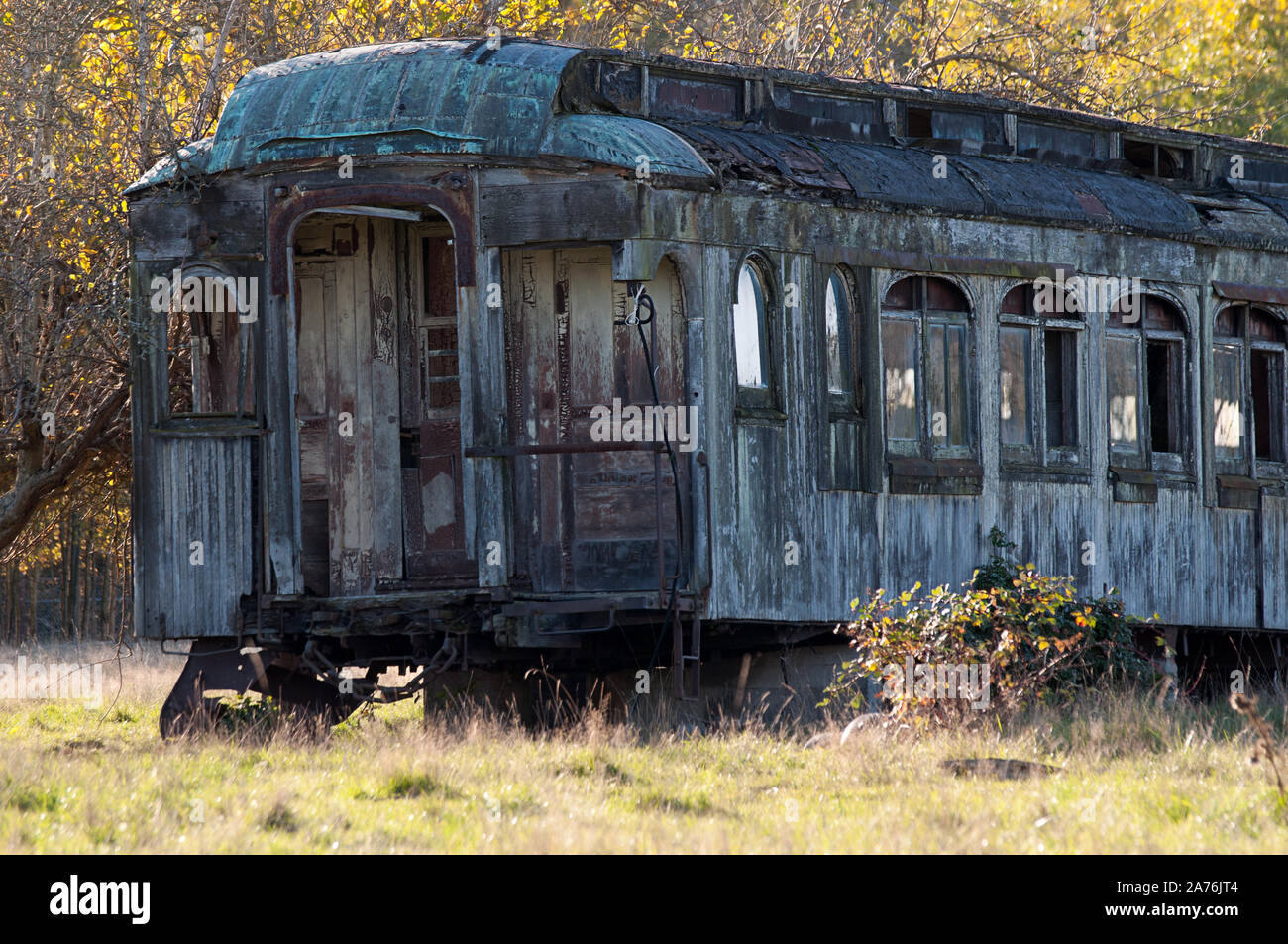 Vecchio treno auto passeggeri abbandonati con un sacco di ruggine in un campo. Un vintage cimeli del passato nel trasporto e corse in treno. Foto Stock