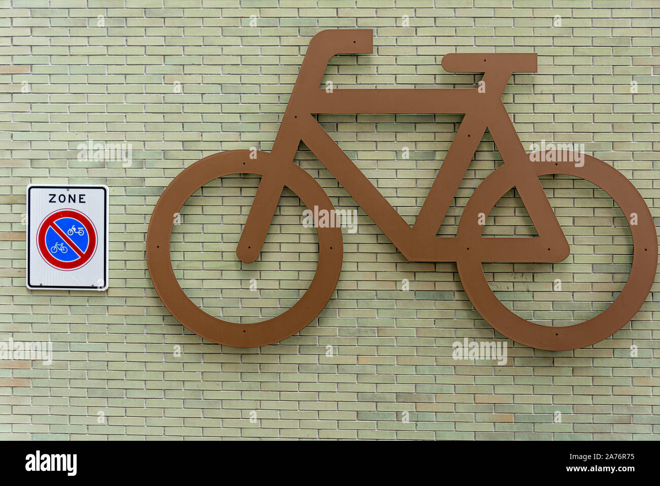 Grande vietato biciclette Parcheggio biciclette avvitato al grande muro di pietra accanto a un vietato per il parcheggio biciclette segno Foto Stock