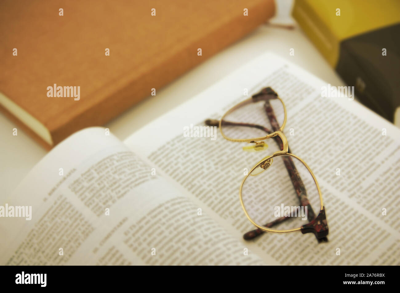 La scena in cui molti libri sono visti, uno di loro ha aperto da una delle sue pagine, su cui sono di colore marrone-occhiali incorniciati Foto Stock