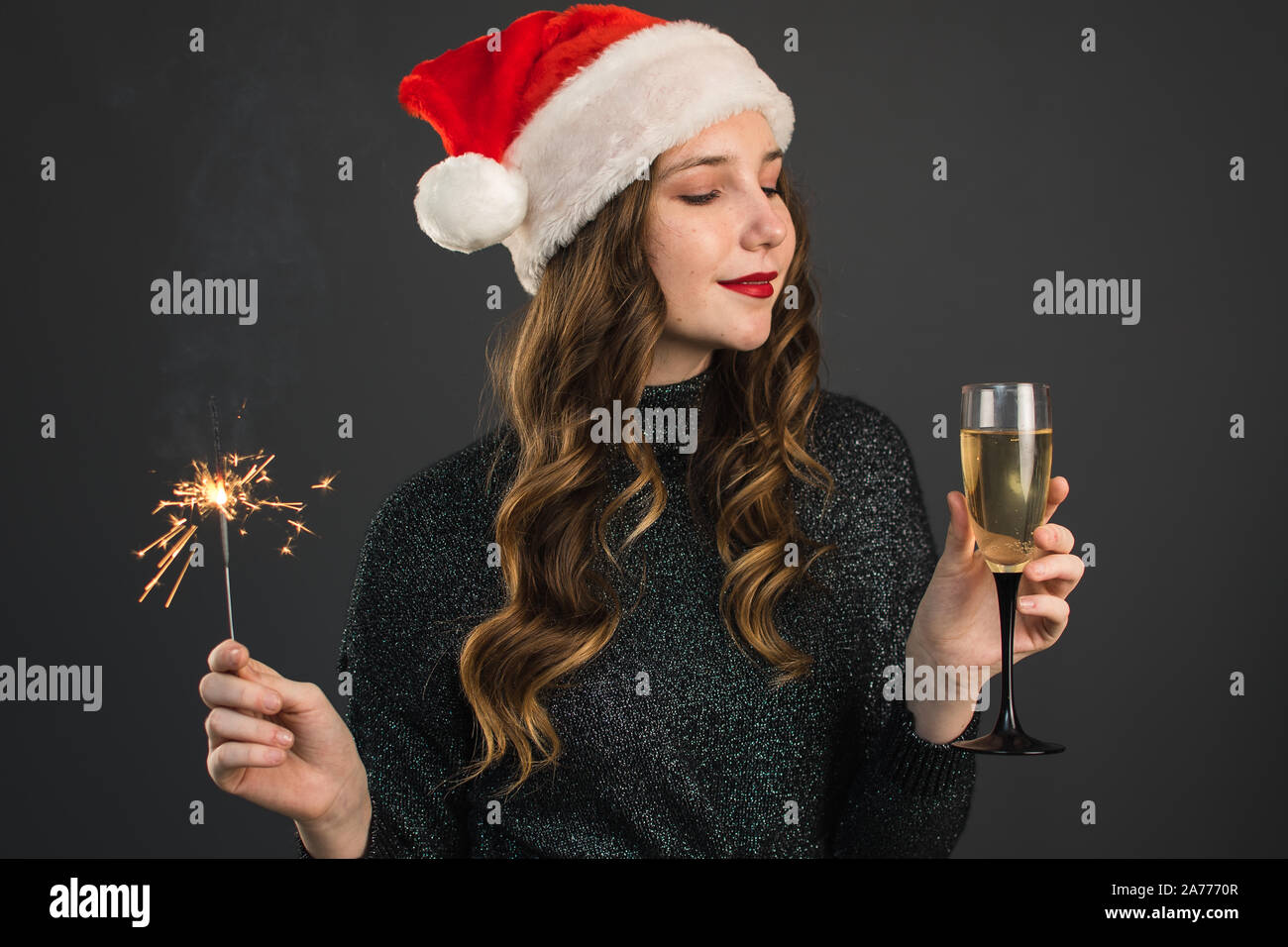 La ragazza di Babbo Natale con cappello di botti in mano e un bicchiere di champagne sorrisi e celebra il Natale e il nuovo anno. La fine delle vacanze, happine Foto Stock