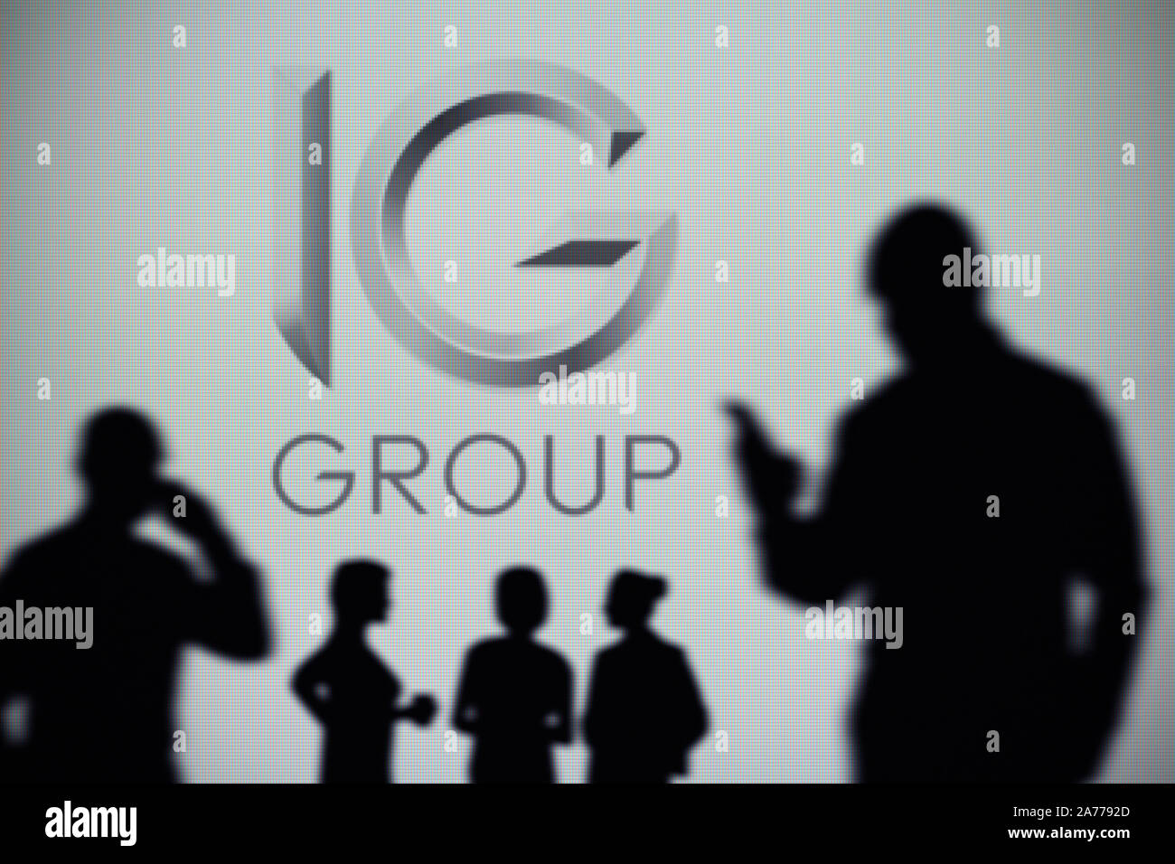 Il gruppo IG logo è visibile su uno schermo a LED in background mentre si profila una persona utilizza uno smartphone (solo uso editoriale) Foto Stock