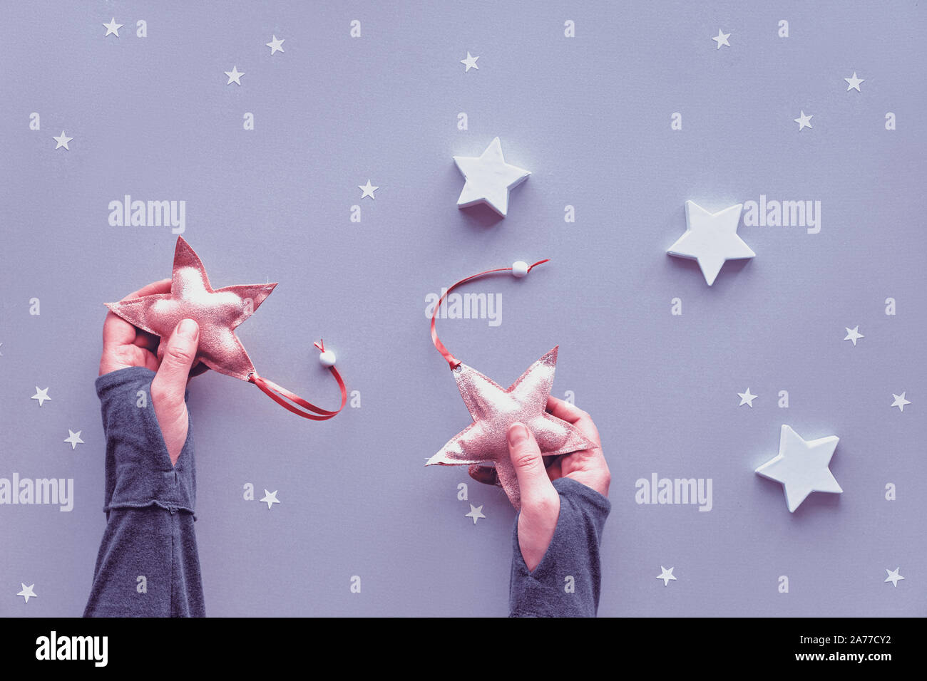 Creative piatto di Natale laici in colori pastello su grigio argento lo sfondo della carta. Mani in morbido tessuto stelle, sfondo grigio con piccoli e grandi p Foto Stock
