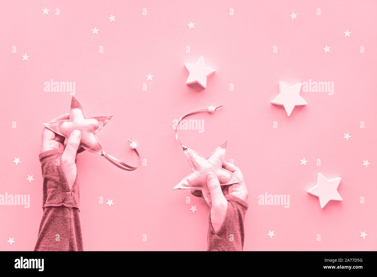 Creative monocromatiche rosa di natale lay piatto su sfondo della carta. Mani in maniche lunghe azienda tessile morbido stelle, laici piatta con grandi e carta di piccole dimensioni Foto Stock