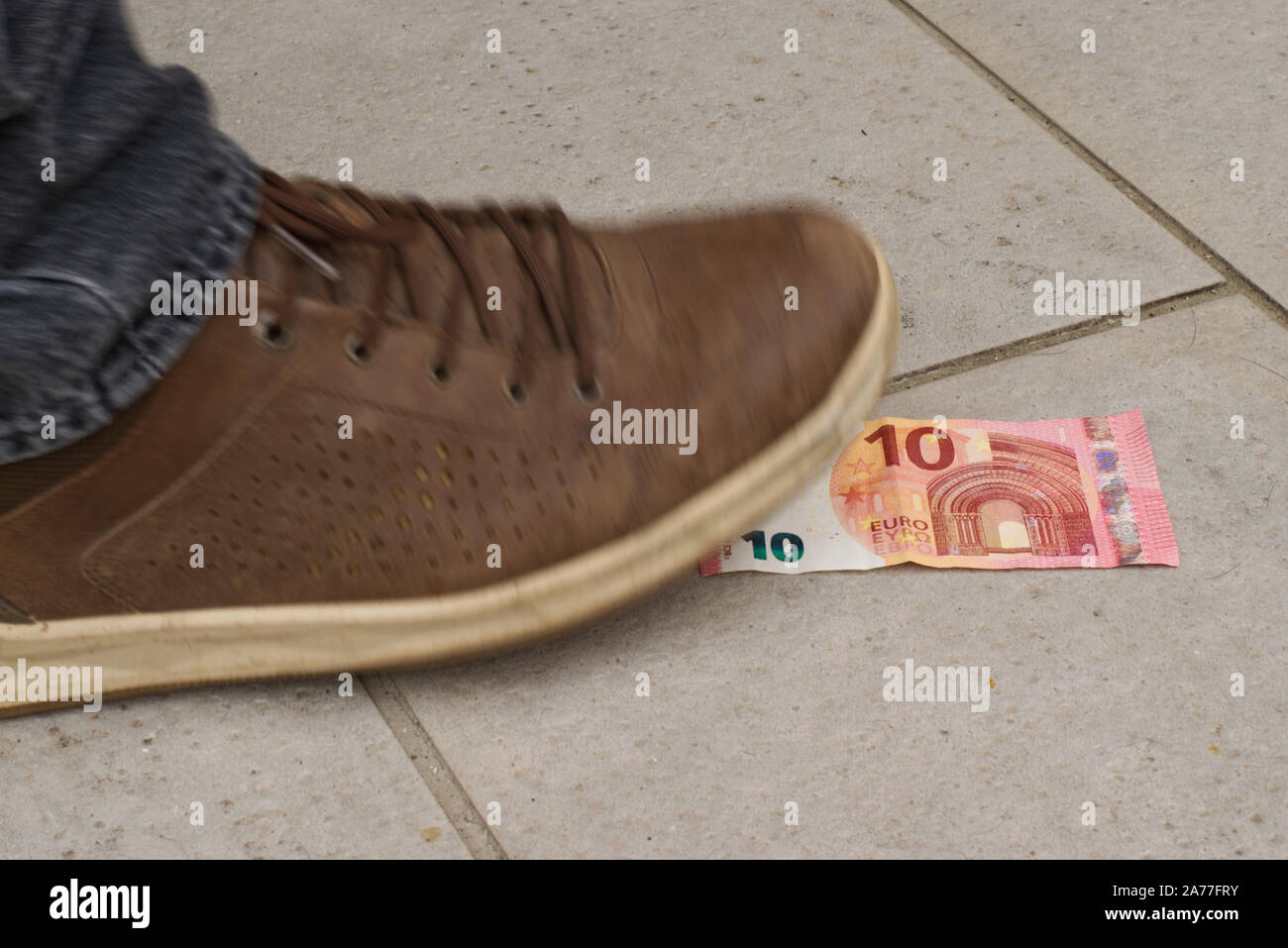 Qualcuno ha trovato 10 euro sulla strada, fissandolo con i suoi piedi. La scarpa è fuori fuoco per il movimento e la dinamica. Foto Stock