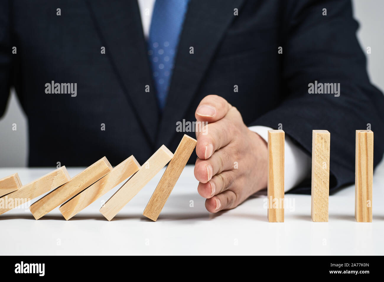 Maschio lato fermare l' effetto domino. Controllo del rischio concetto. Foto Stock