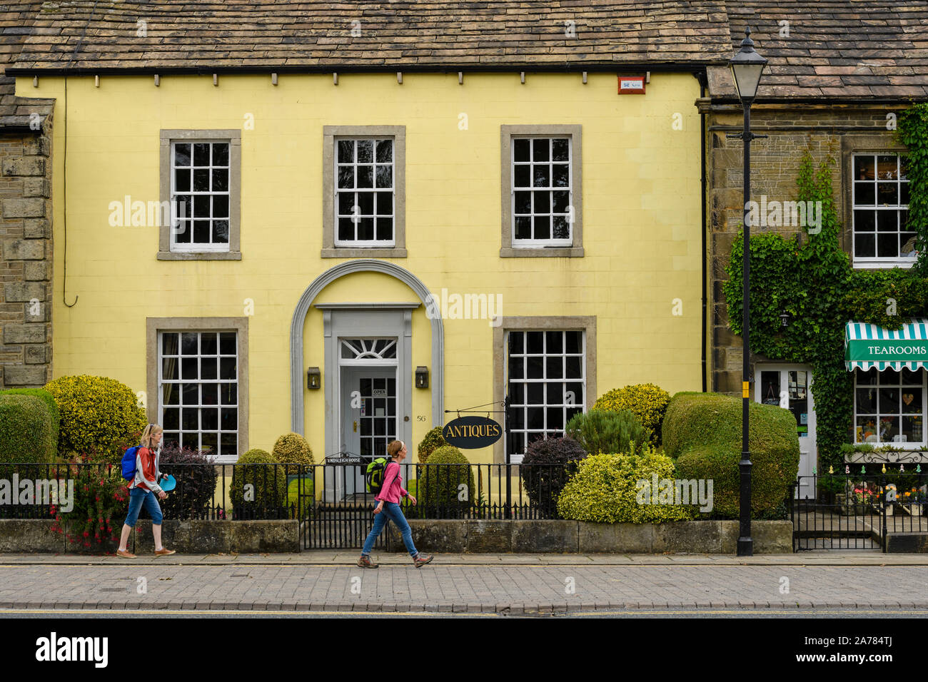 2 donne a piedi passato esterno di attraenti negozi di antiquariato (edificio Georgiano) & Dalesman Caffetteria Sala da tè - Villaggio di Gargrave, North Yorkshire, Inghilterra, Regno Unito Foto Stock