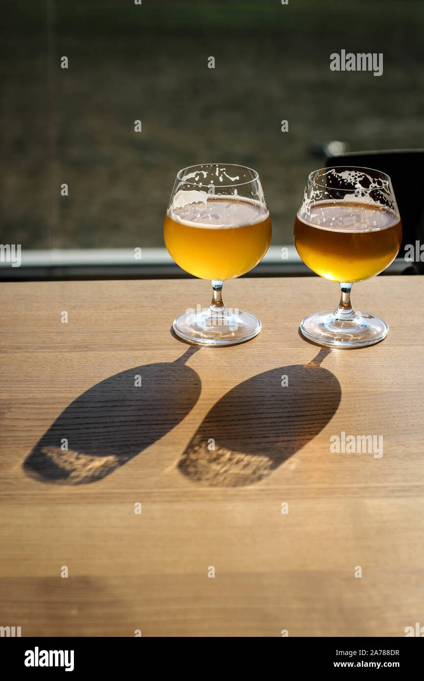 Due snifter di vetro con una birra su il sole sul tavolo Foto Stock