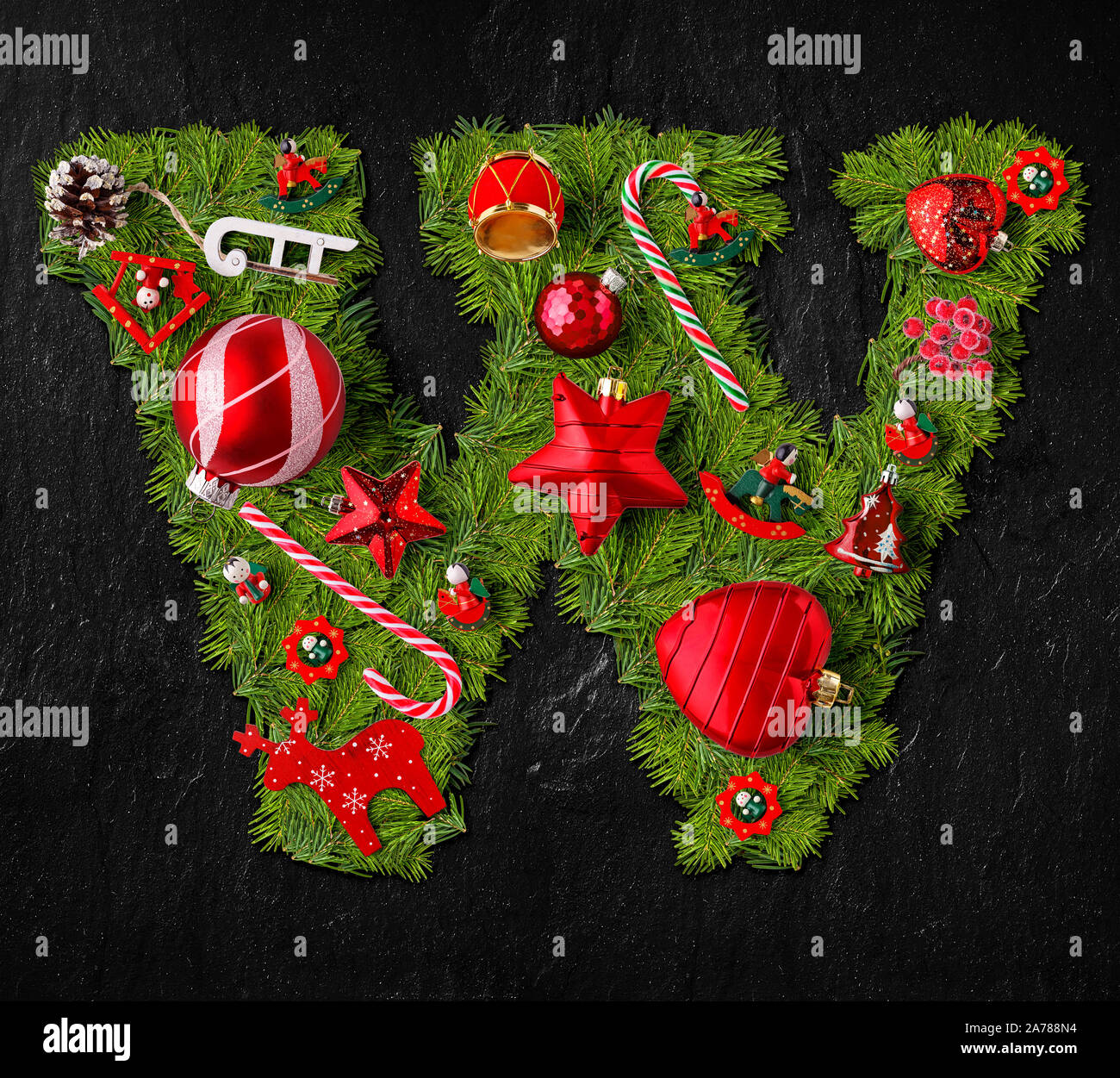 Lettera W fatta di albero di Natale ornamenti su un nero ardesia sfondo Foto Stock