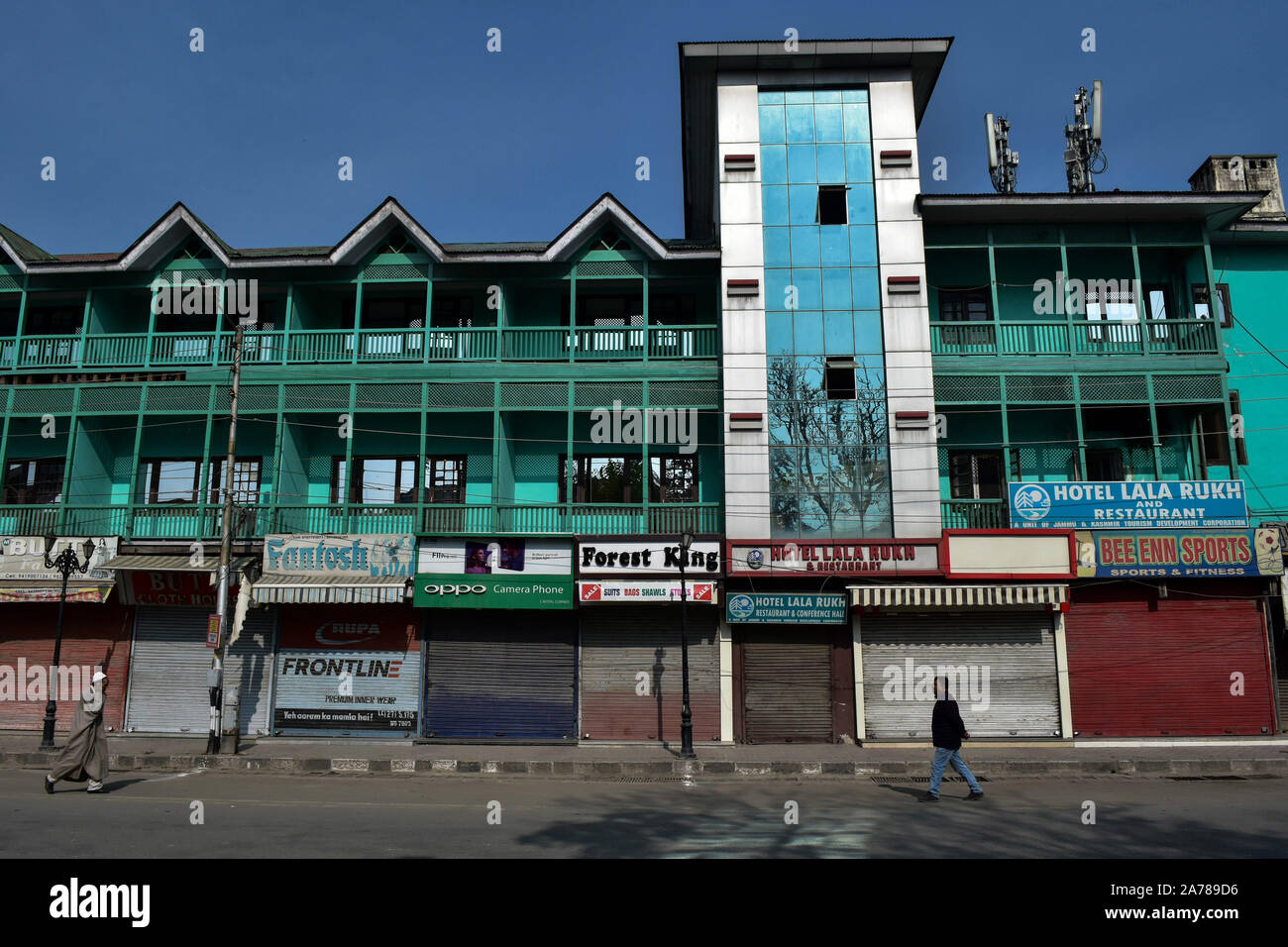 Residenti a piedi passato negozi chiusi durante lo shutdown.valle del Kashmir hanno continuato a rimanere chiuso sulla 88th giorno consecutivo contro l'abrogazione dell'articolo 370 e la biforcazione del Jammu e Kashmir Stato in due territori dell'Unione da parte del governo indiano. Foto Stock