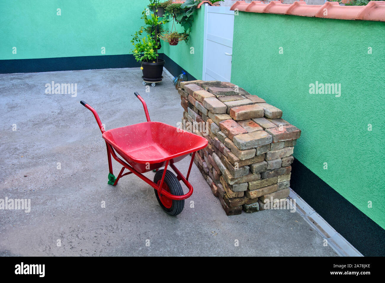 Cortile impilati con vecchi mattoni e red trolley per il trasporto. Solo i muratori sono in attesa di iniziare la muratura. Foto Stock