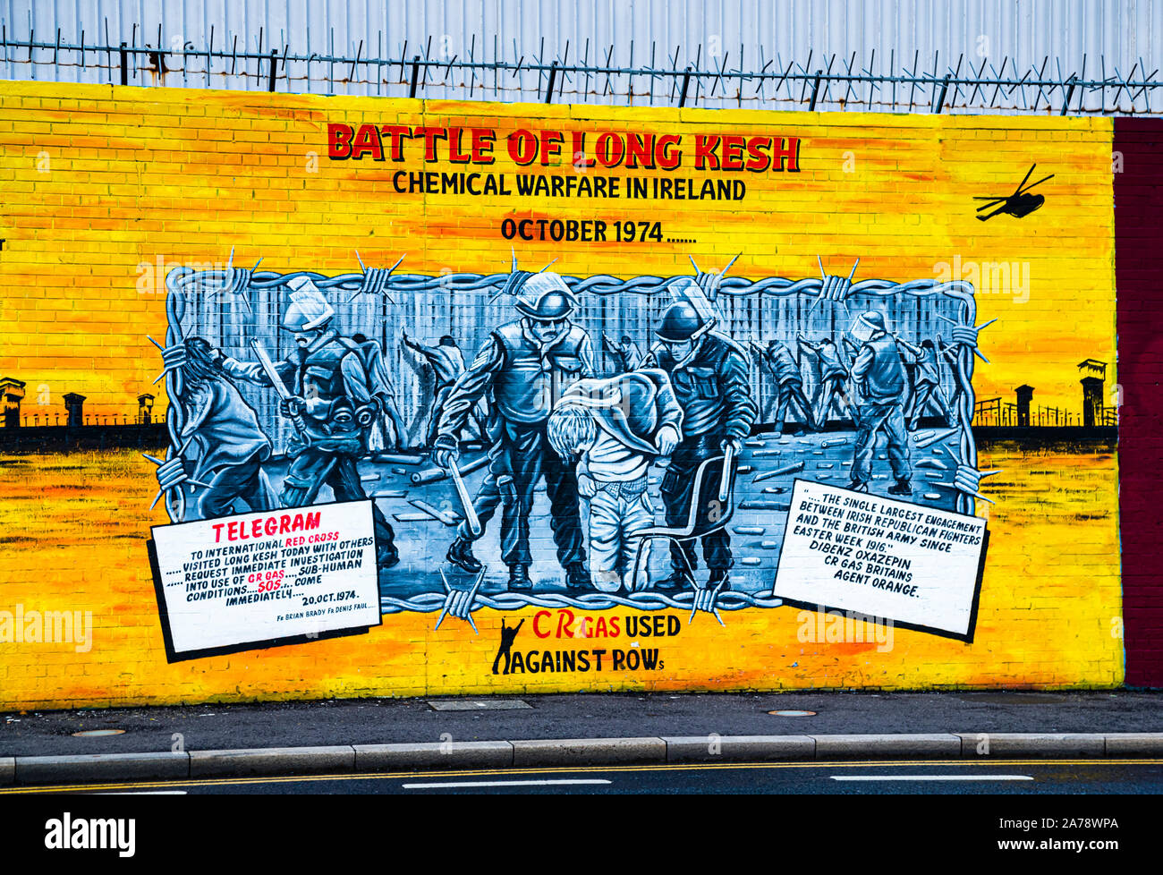 Un murale intitolato "Battaglia di Long Kesh – Guerra chimica in Irlanda – Ottobre 1974" sul Muro Internazionale, Northumberland Street, Belfast, Irlanda del Nord, mostra prigionieri incappucciati dietro il filo spinato insieme al testo di un telegramma alla Croce Rossa Internazionale datato 20 ottobre 1974, che richiede un’indagine immediata sulle "condizioni sub-umane" seguenti l’uso del gas CR; un pannello testuale accompagnatorio descrive l’incidente come il più grande scontro tra combattenti repubblicani irlandesi e l’esercito britannico dalla Settimana di Pasqua del 1916. Foto Stock