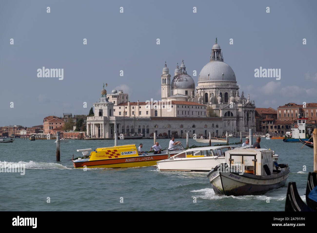 Di colore giallo brillante e acqua rossa ambulanza accelerando il passato di acqua di mare altre barche con la cupola bianco sullo sfondo di Punta della Dogana Foto Stock