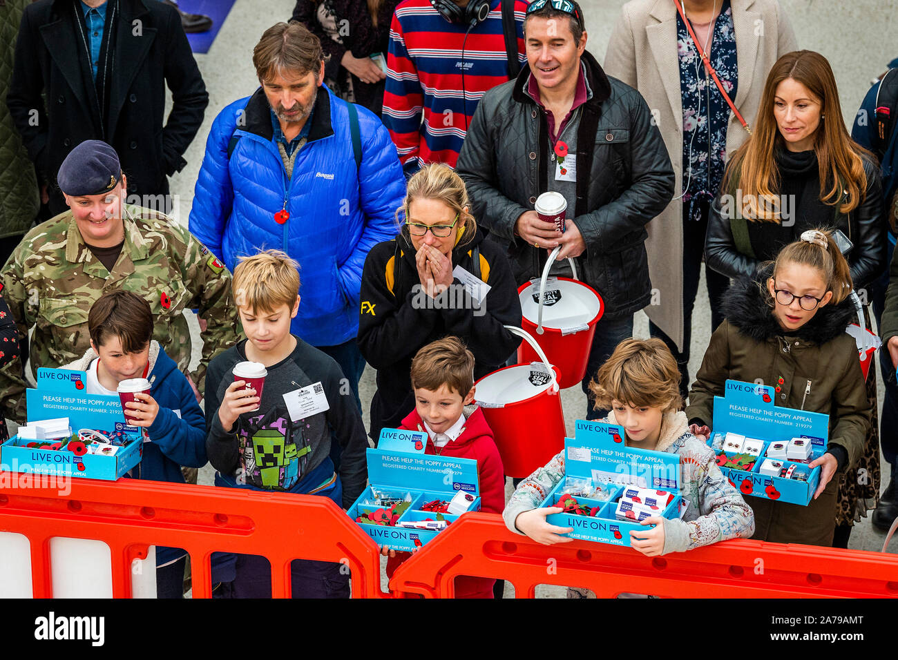 Famiglia di volontariato collezionisti guardare il display del combattimento disarmati dai Royal Marines, a Waterloo Station - 2000 personale di servizio di unire le forze con i veterani, volontari e celebrità nel tentativo di sollevare £ 1 m in un unico giorno per il Royal British Legion durante la London Poppy Day. Credito: Guy Bell/Alamy Live News Foto Stock