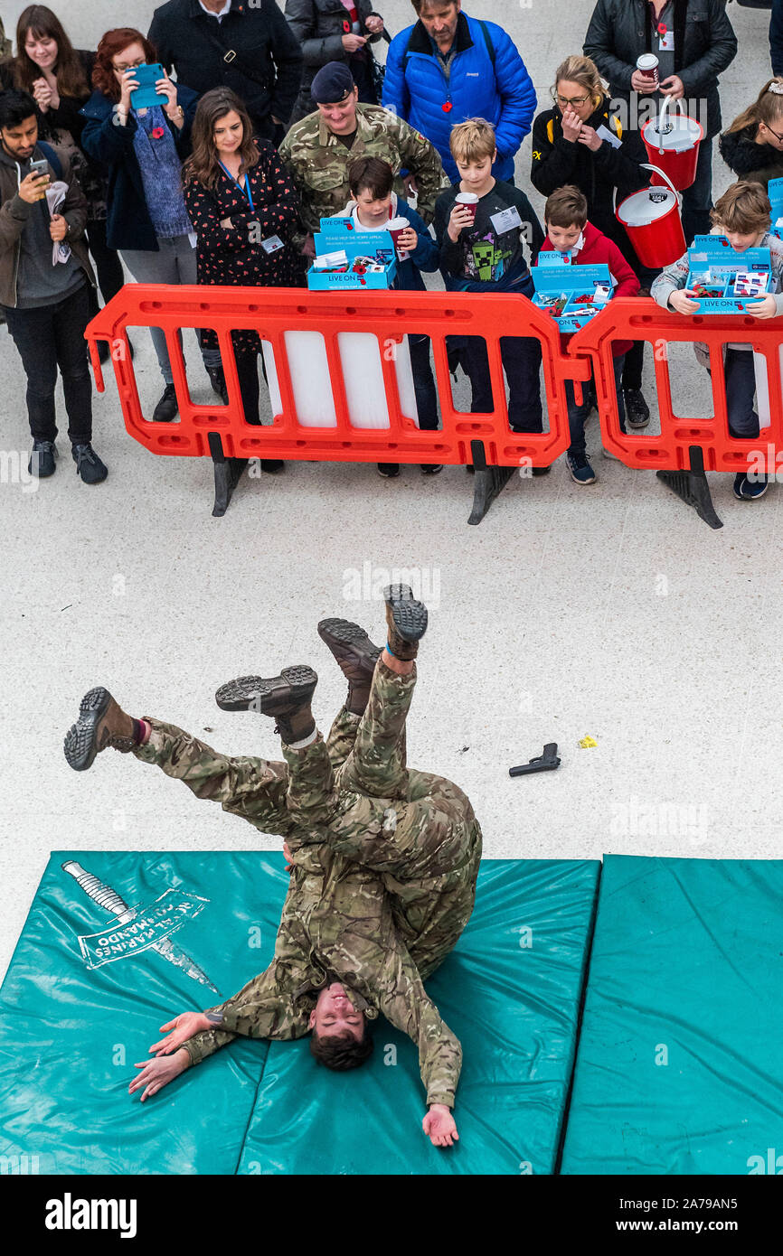 Famiglia di volontariato collezionisti guardare il display del combattimento disarmati dai Royal Marines, a Waterloo Station - 2000 personale di servizio di unire le forze con i veterani, volontari e celebrità nel tentativo di sollevare £ 1 m in un unico giorno per il Royal British Legion durante la London Poppy Day. Credito: Guy Bell/Alamy Live News Foto Stock