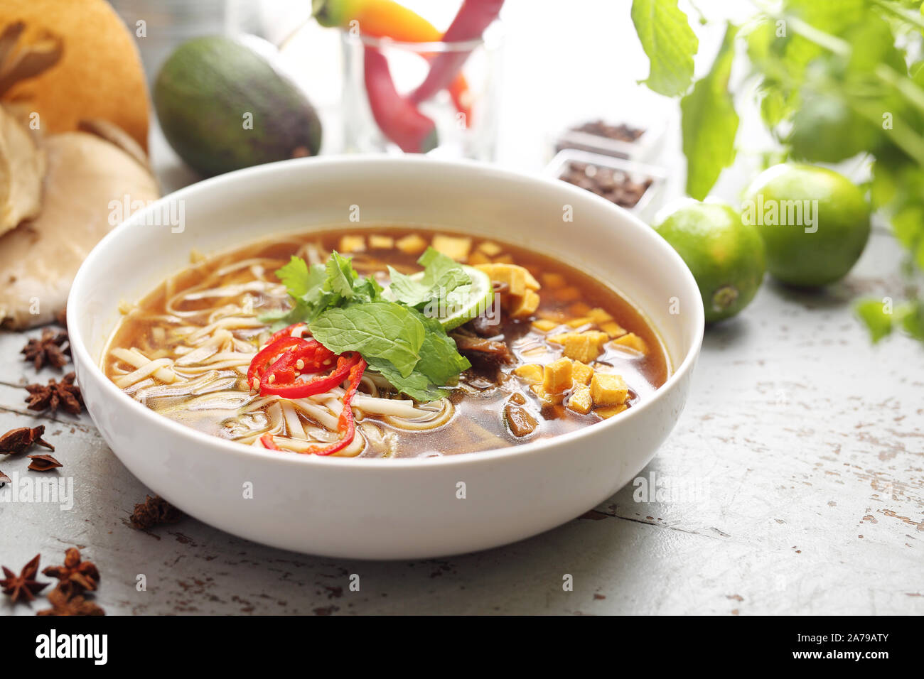 Oriental vietnamita zuppa Pho con la menta, coriandolo, tofu, caramellato funghi orecchioni, calce, riso tagliatelle e peperoncino. Oriental zuppa vietnamita Foto Stock