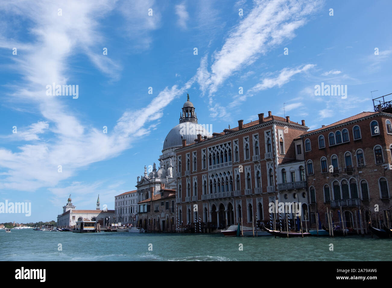 Brillante immenso cielo blu con nuvole bianche sopra gli edifici e la chiesa a cupola accanto al mare canali ov Venezia, Italia Foto Stock