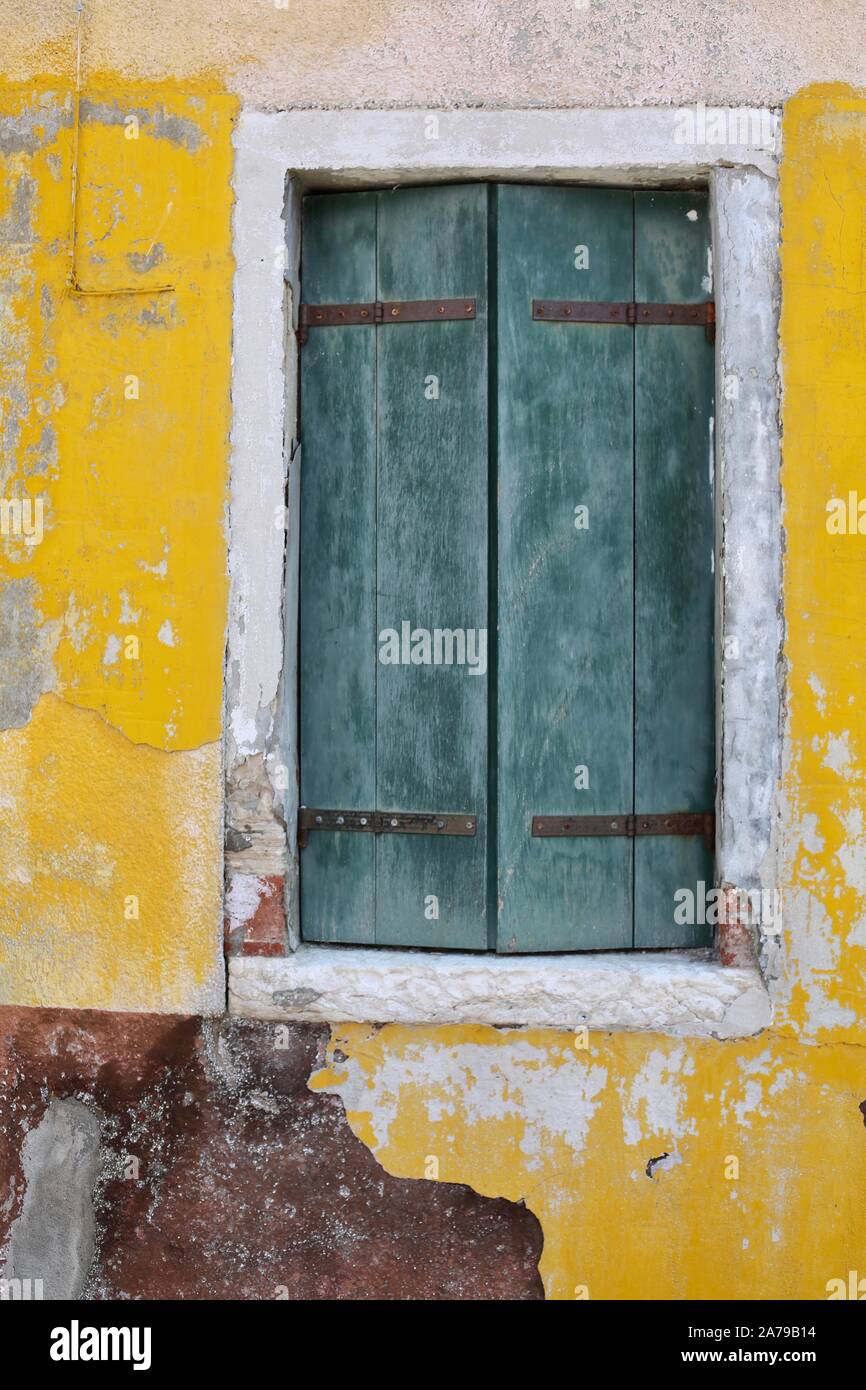 Persiane verdi su una casa gialla con peeling paint Foto Stock