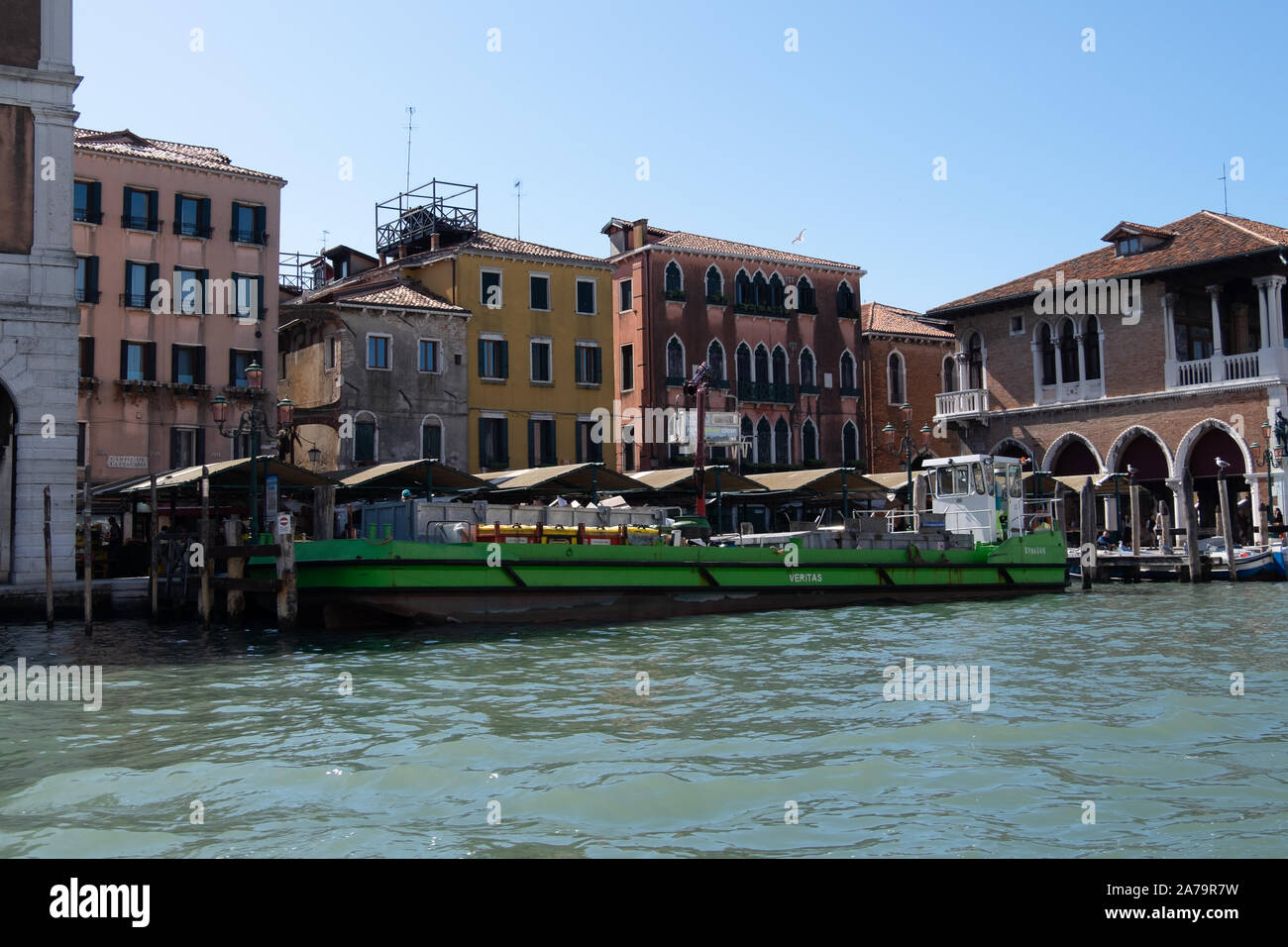 Massiccio consegna verde barcone sul Canal Grande Venezia la consegna al coperto bancarelle di frutta e verdura e il famoso mercato del pesce Foto Stock