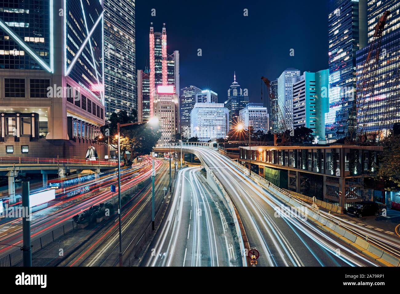 Occupato il traffico nella città moderna. Sentieri di luce di vetture contro notte urban skyline di Hong Kong. Foto Stock