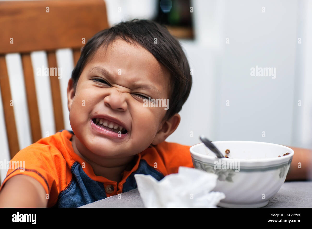 3 anno vecchio ragazzo seduto al tavolo, felicemente a mangiare il suo cioccolato cereali al mattino. Foto Stock