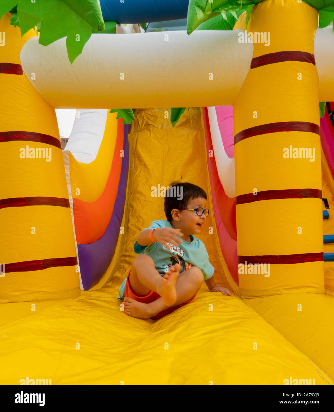 Ragazzo sulla diapositiva a castello gonfiabile Foto Stock