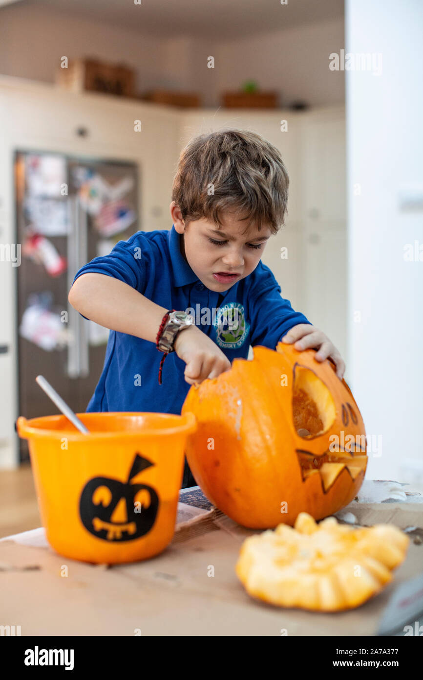 Ragazzo di 6 anni che raschia la cotenna all'interno di una zucca scolpita davanti a Halloween, Inghilterra, Regno Unito Foto Stock