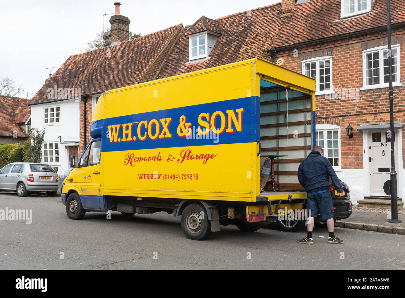 W.H. Cox & Figlio traslochi van con uomo mobili in movimento al di fuori di una casa a Amersham Città Vecchia, REGNO UNITO Foto Stock